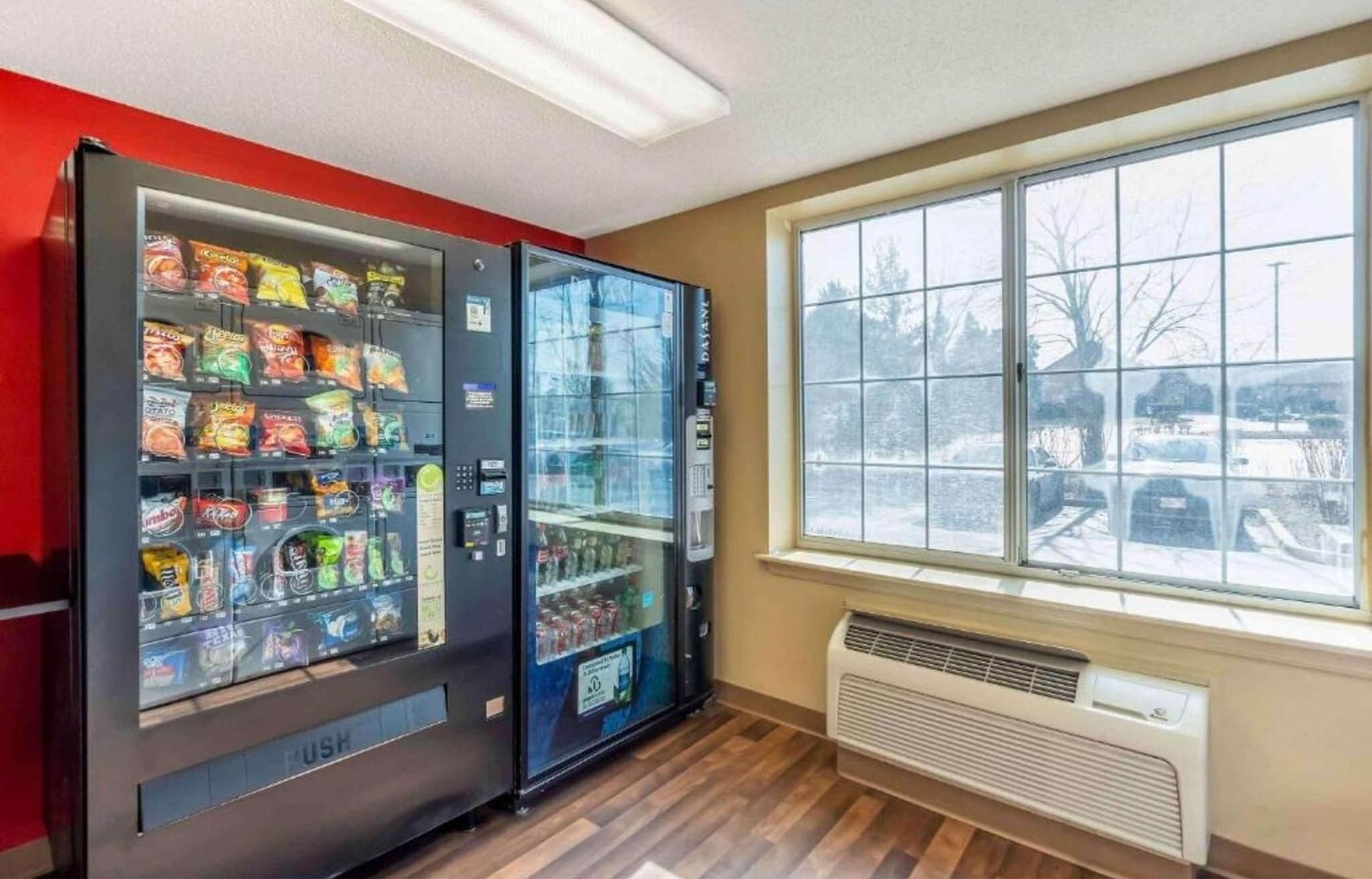 Et værelse med to automater fyldt med snacks og et stort vindue med udsigt over et sneklædt landskab.