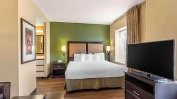 A hotel room with a bed, bedside lamps, a television, a desk, and a chair.