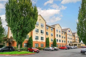 Ein mehrstöckiges Hotel mit Parkplatz davor.