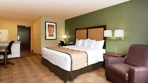 Quarto de hotel com cama, escrivaninha, cadeira e duas luminárias de cabeceira.