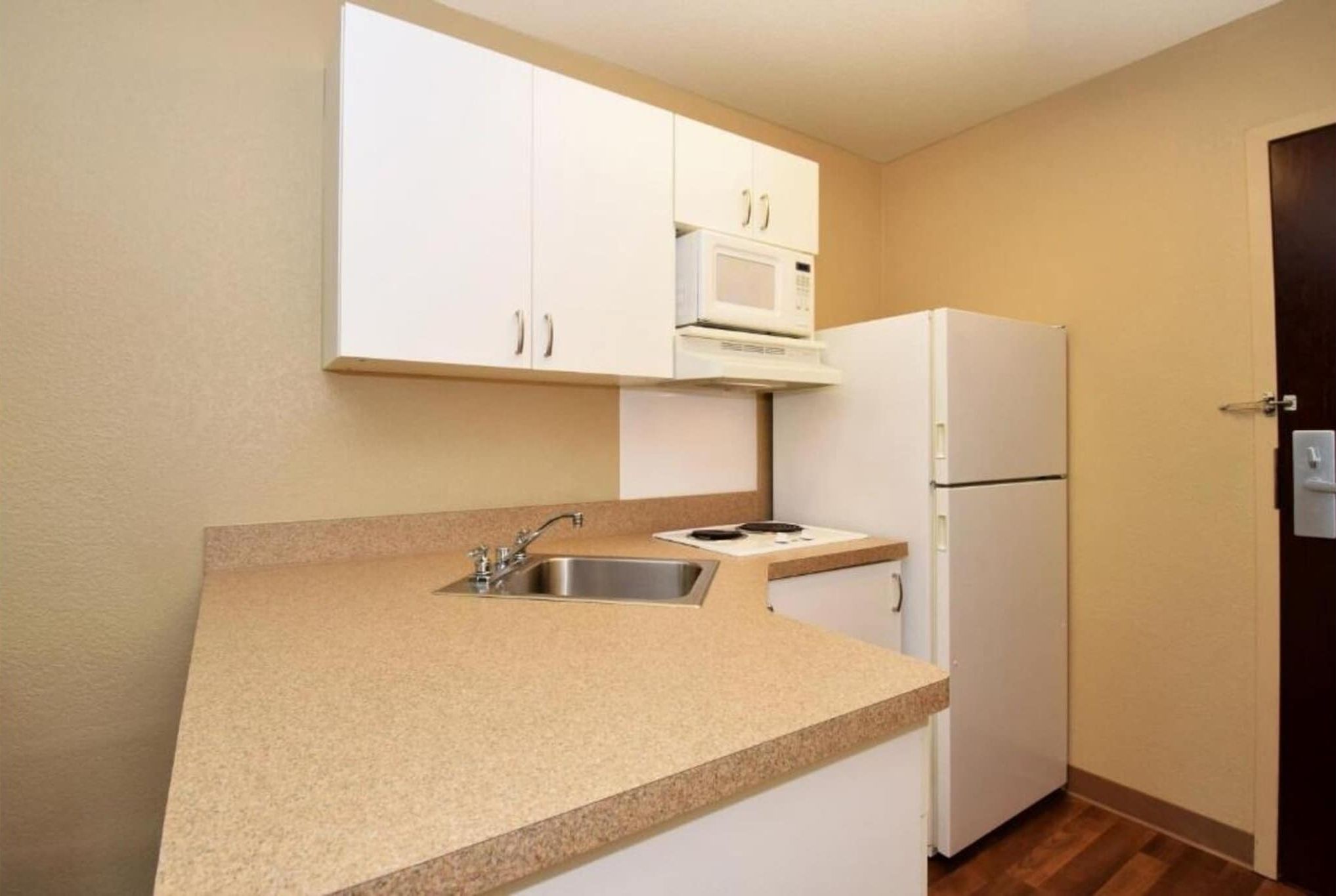 Een kleine kitchenette met een spoelbak, magnetron en koelkast.