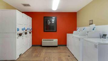 A laundry facility with stacked washers and dryers, a central air vent, and a framed picture on the wall.