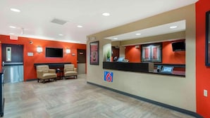En hotellobby med en receptionsdisk, en sittgrupp och en skylt som visar hotellets namn.