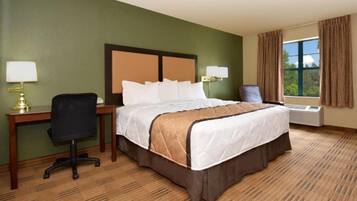 A hotel room with a bed, desk, chair, and a window with curtains.