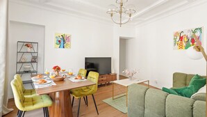 Ein modernes Wohnzimmer mit Essbereich, einem Flachbildfernseher und Kunstwerken an den Wänden.