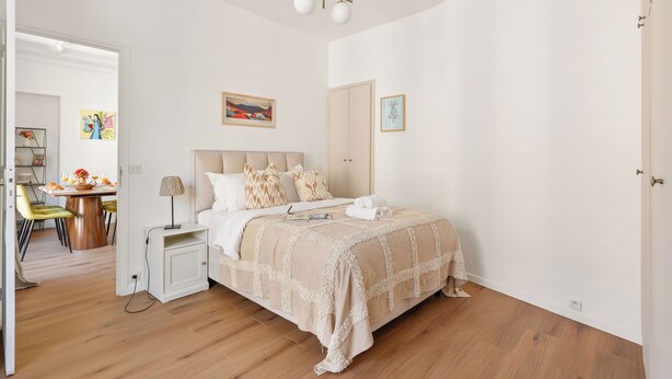 Ein Schlafzimmer mit Bett, Nachttisch, Lampe und einem Kunstwerk an der Wand.