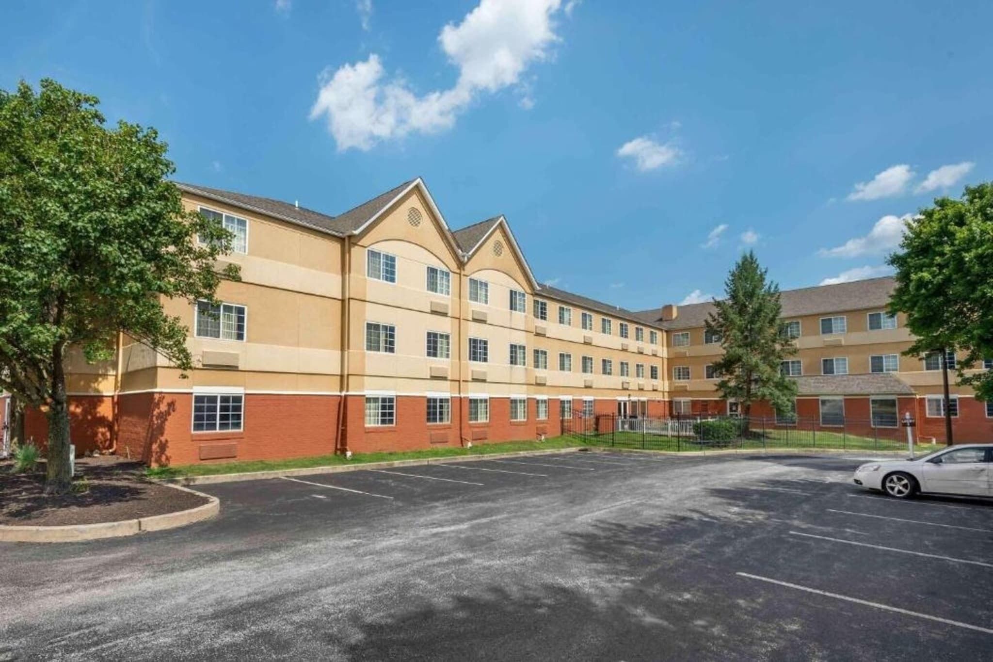 A multi-story hotel with a parking lot and trees.