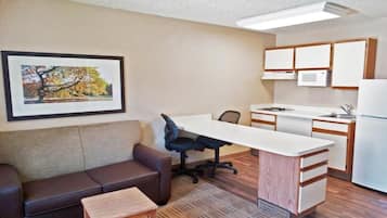 A compact living space with a kitchenette, a sofa, a dining table, and a framed picture on the wall.
