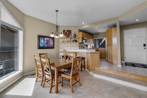 Una cucina moderna con mobili in legno, zona pranzo con tavolo e sedie, e un'ampia finestra che offre luce naturale.