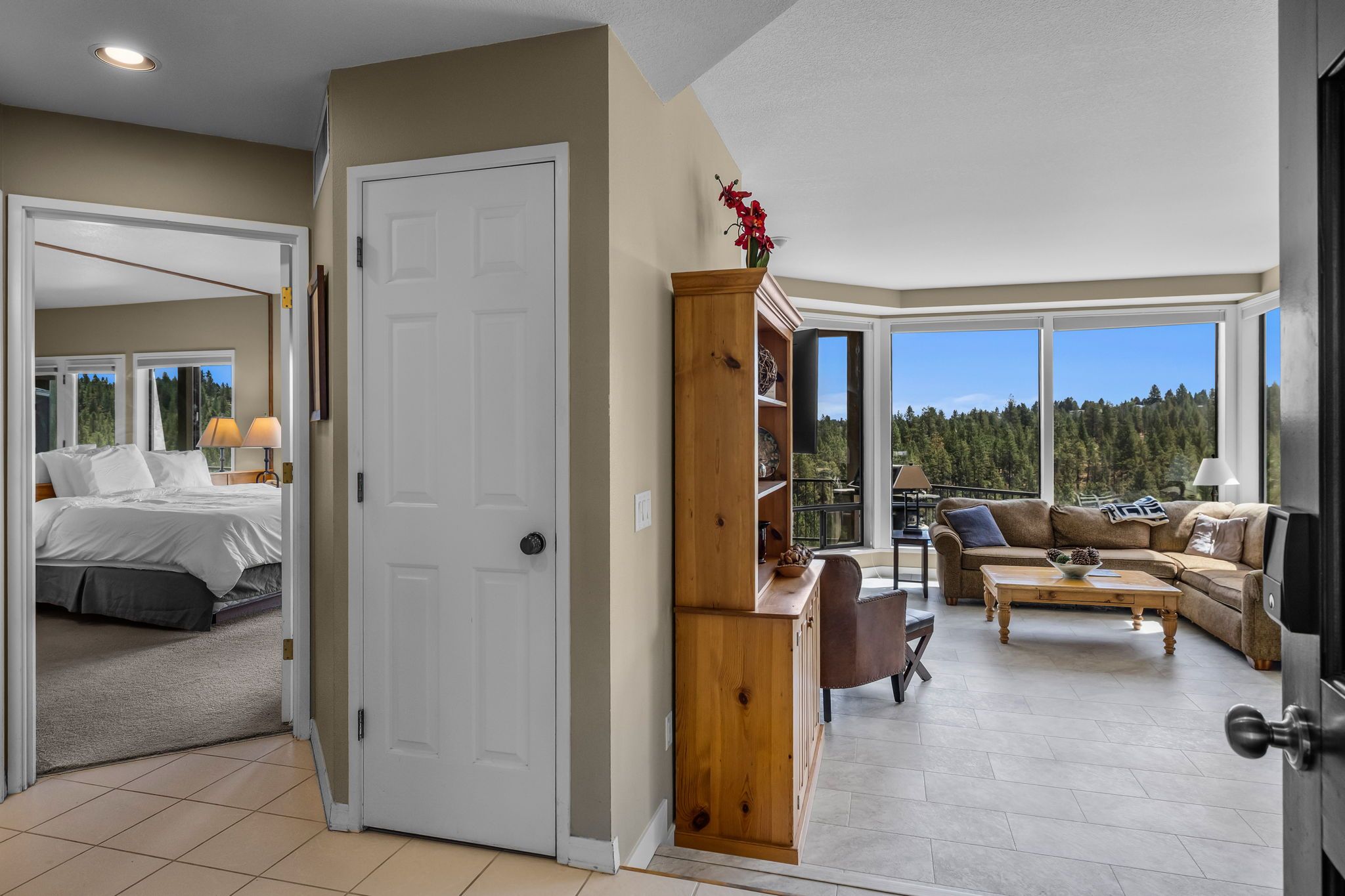 A spacious living area with a large window, a cozy seating area, and a separate bedroom with a bed and nightstands.