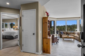 A spacious living area with a large window, a cozy seating area, and a separate bedroom with a bed and nightstands. - Mt Bachelor Village 321 | Hot Tub | Scenic Views (Bend)