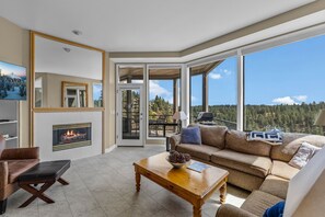 A spacious living room with a fireplace, a large sofa, a coffee table, and a television. - Mt Bachelor Village 321 | Hot Tub | Scenic Views (Bend)