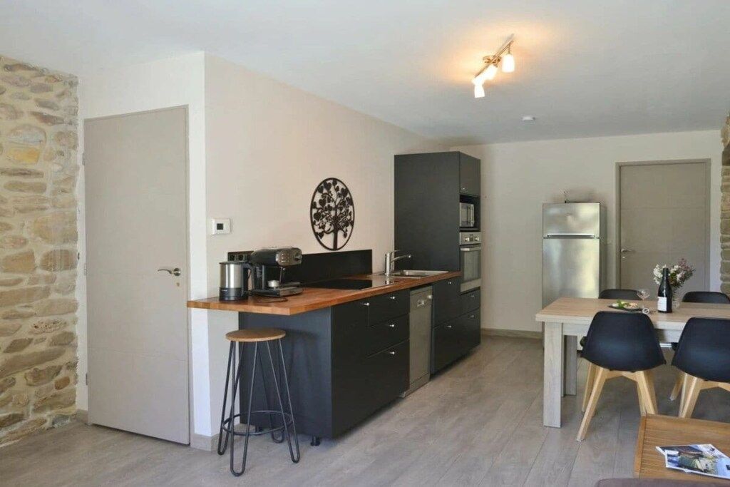 Una cocina compacta con una isla central, un comedor con mesa y sillas, y un refrigerador.