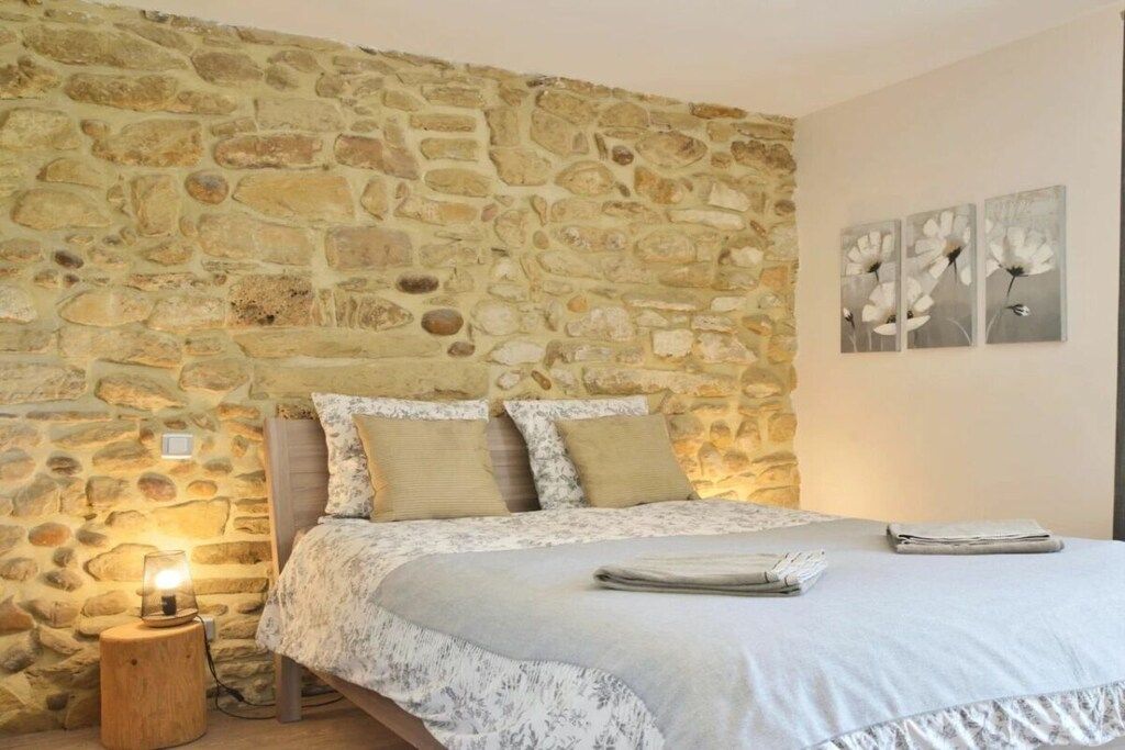 Ein Schlafzimmer mit einer Steinsturz, einem Bett mit floralem Überwurf, einer Nachttischlampe und Wandbildern.