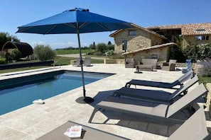 A swimming pool with lounge chairs and an umbrella, surrounded by stone buildings. - Holiday home with 1 bedroom (SAINT-LATTIER)