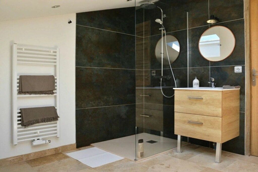 A modern bathroom with a glass-enclosed shower, a wooden vanity, and a white towel rack.