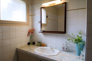 Ein Badezimmer mit einem weißen Waschbecken, einem Spiegel und einer Topfpflanze.