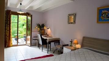 Une chambre à coucher avec un lit, un bureau et une chaise. Il y a une fenêtre avec des rideaux et une vue sur la verdure à l’extérieur.