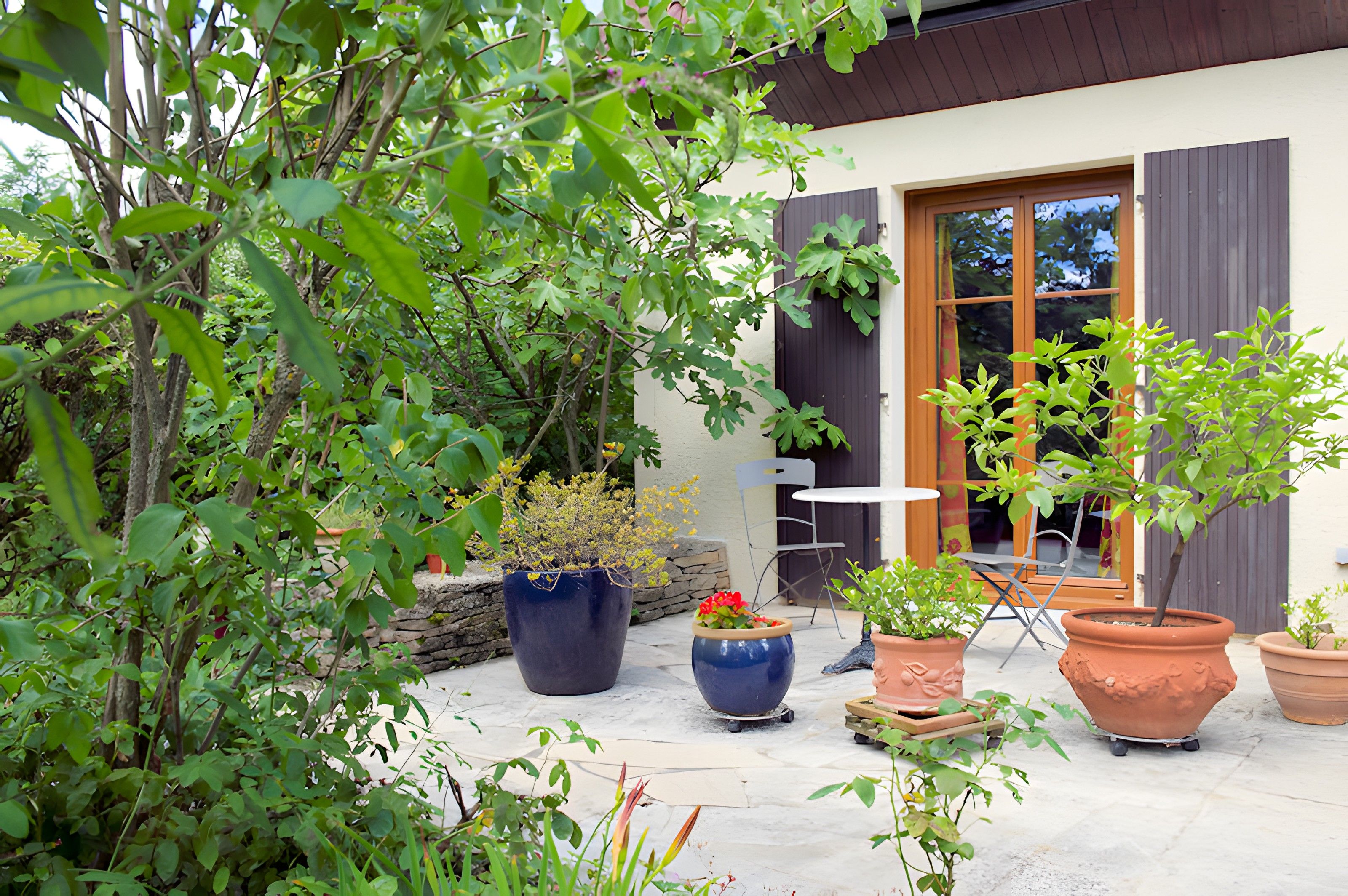Une terrasse agrémentée de plantes en pot, avec une table et une chaise.