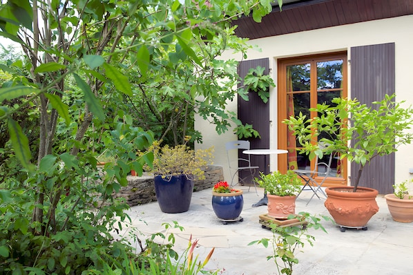A patio with potted plants, a table, and a chair.