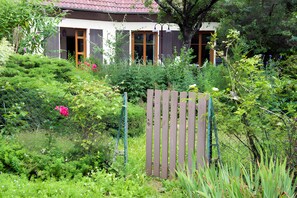 Ein Wohnhaus mit Garten, Holzzaun und einem Dach in roter Farbe.