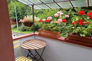 Een oranjerie met een tafel en stoelen, omgeven door potplanten en bloemen.