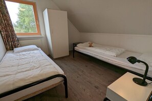A dormitory room with two single beds, a desk with a lamp, a wardrobe, and a window with curtains. - Holiday home with 1 bedroom (Medemblik)
