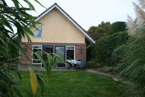 A residential house with a sloped roof, a front porch, and a well-maintained lawn. - Holiday home with 1 bedroom (Medemblik)