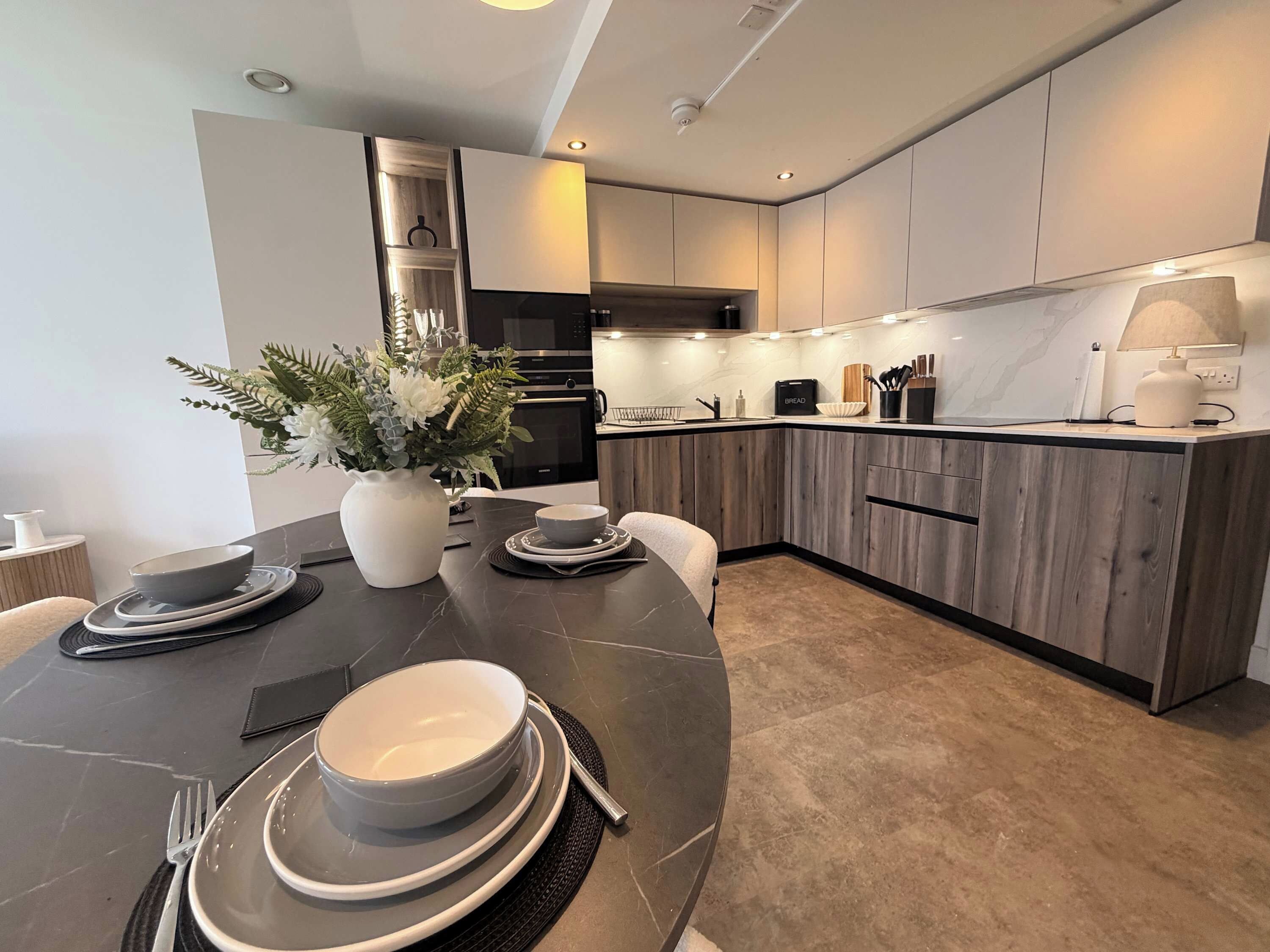 A modern kitchen with a dark countertop, white cabinets, and a central island.