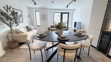 A modern dining area with a round table, six chairs, and a vase of flowers.