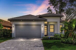 Ein modernes, zweistöckiges Haus mit Garage, Auffahrt und gepflegtem Rasen.