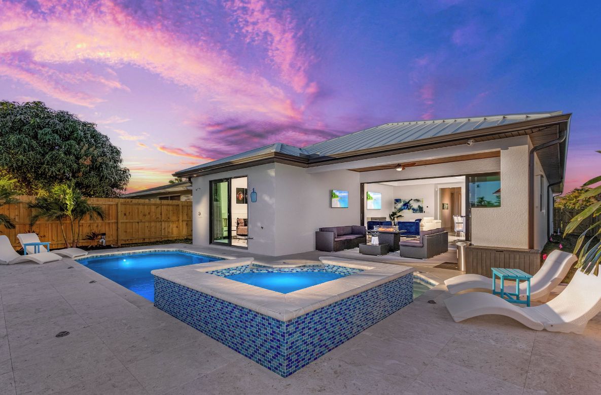 A modern house with a swimming pool, outdoor seating, and a view of the sky.