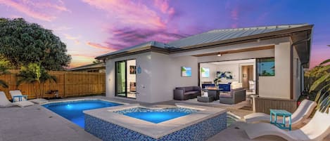 A modern house with a swimming pool, outdoor seating, and a view of the sky.