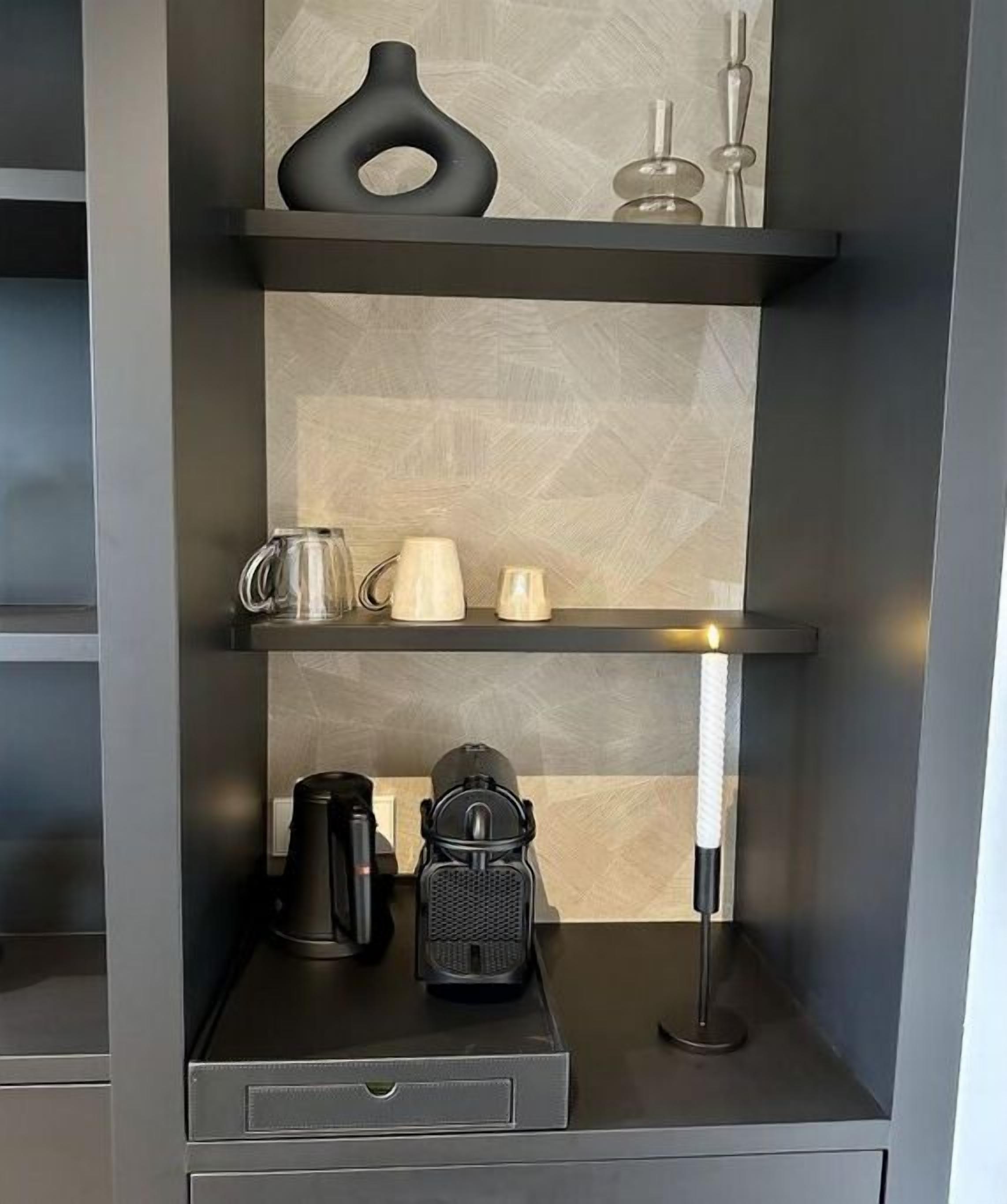 A modern kitchen with a built-in coffee maker, a kettle, and a portable espresso machine on the countertop.