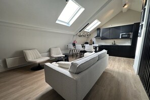 A modern loft apartment with a dining area, kitchen, and a large window providing natural light. - Holiday apartment with 3 bedrooms (Oudkarspel)