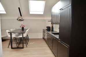 A modern kitchen with a dining area, featuring a table with chairs, a kitchen island, and a built-in oven. - Holiday apartment with 3 bedrooms (Oudkarspel)