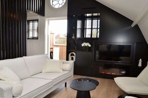 A modern living room with a white sofa, a black coffee table, and a TV. - Holiday apartment with 3 bedrooms (Oudkarspel)