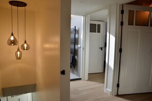 A hallway with a white door, a black towel rack, and a light fixture with three bulbs. - Holiday apartment with 3 bedrooms (Oudkarspel)