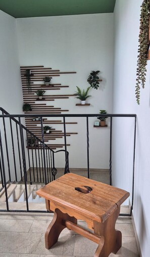 A wooden table with a metal railing in a room with a staircase and potted plants. - BergNah Piding Vacation Rental – Light-Filled with 6 Balconies + Mountain Views (Piding)