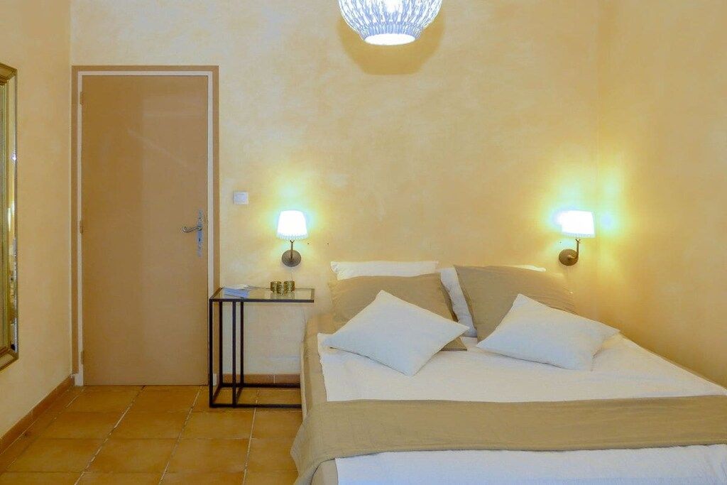 A hotel room with a bed, bedside lamps, a nightstand, and a door.