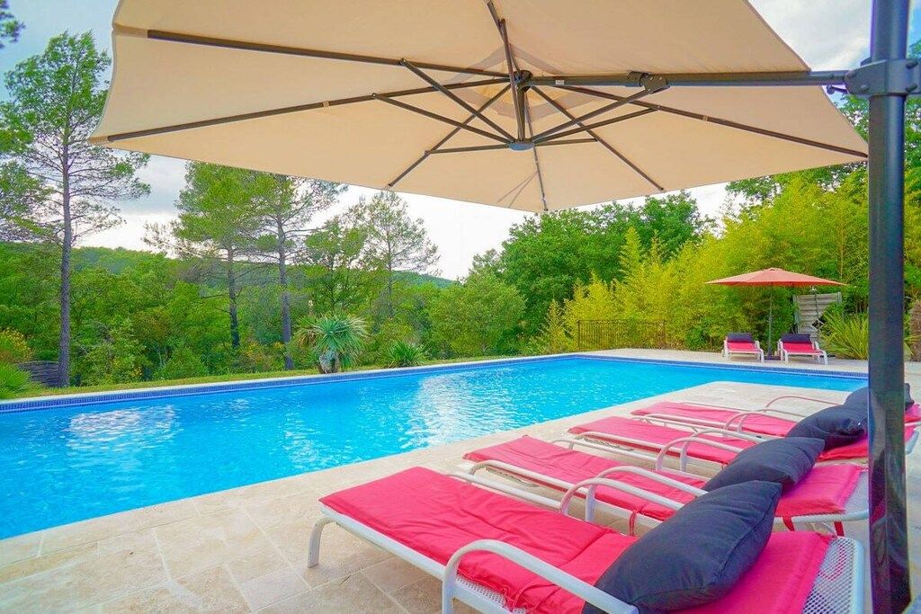 A swimming pool with lounge chairs and umbrellas.