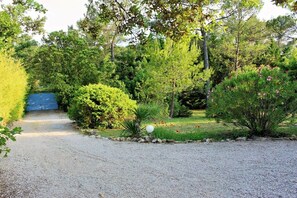 A gravel path leading to a blue gate, surrounded by dense greenery and various shrubs. - with pool in the hinterland of the coast (Flayosc)