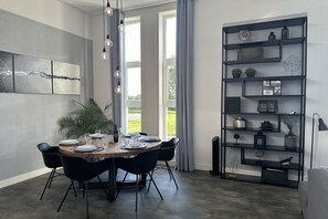 Ein Essbereich mit einem runden Tisch, schwarzen Stühlen und einer modernen Leuchte.