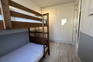 Ein Schlafraum mit Etagenbett, einer Holzlade und einer weißen Tür.