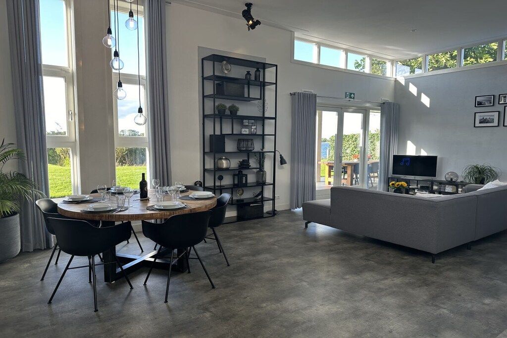 Un salon moderne avec un canapé gris, une table à manger dressée pour quatre personnes et une bibliothèque.