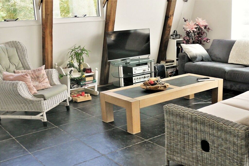 Een woonkamer met een televisie, een salontafel, een bank en een fauteuil.