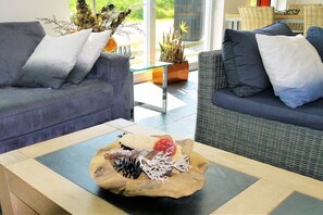 A modern living room with two sofas, a glass coffee table, and a wicker chair. - Markermeerlogies at the lake (Bovenkarspel)