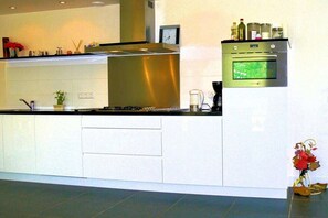 Eine moderne Küche mit weißen Schränken, Edelstahlgeräten und einem eingebauten Backofen.