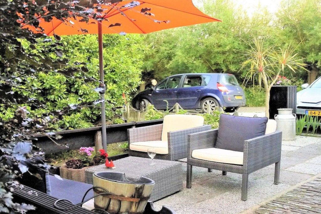 Een terras met rieten meubels en een vuurkorf.