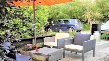 Een terras met rieten meubels en een vuurkorf.